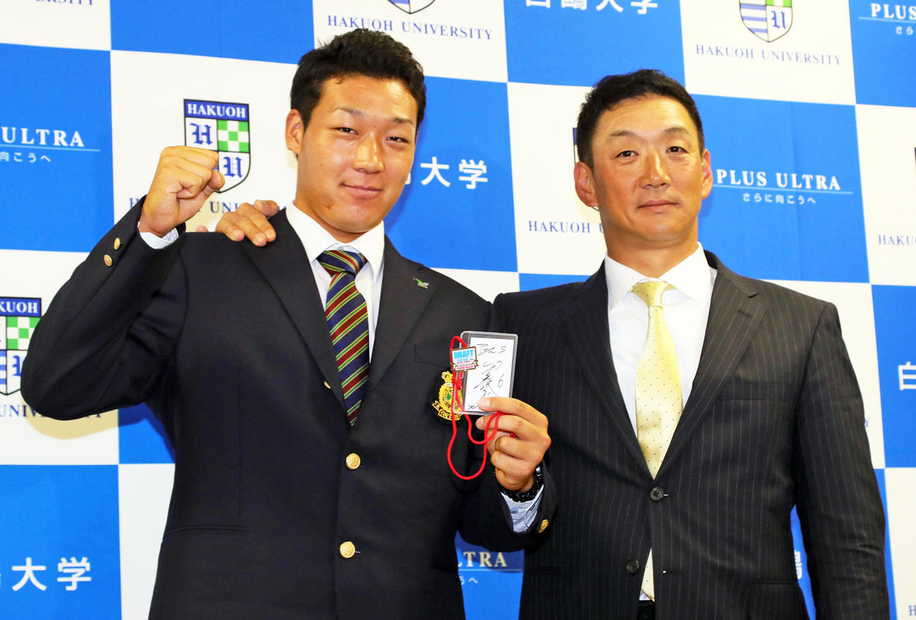 指名あいさつに訪れた阪神金本知憲監督（右）からドラフトIDカードをプレゼントされ笑顔でポーズを取る白鴎大・大山悠輔（2016年10月20日撮影）