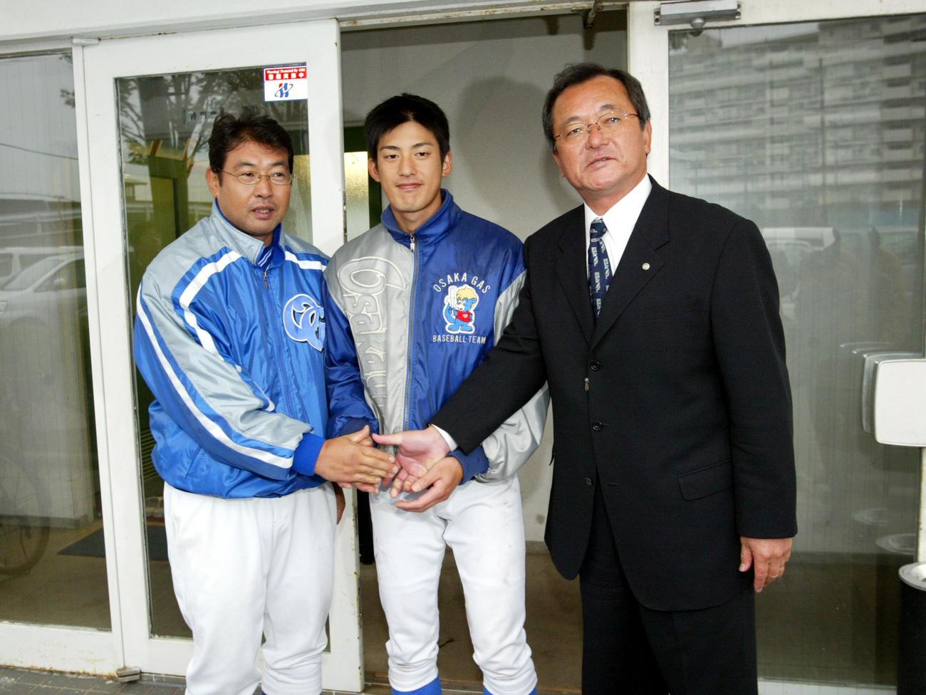 阪神・池之上格スカウト課長（右）の指名挨拶を受けて笑顔で握手を交わす大阪ガス・能見篤史。左は湯川素哉監督（2004年11月18日）