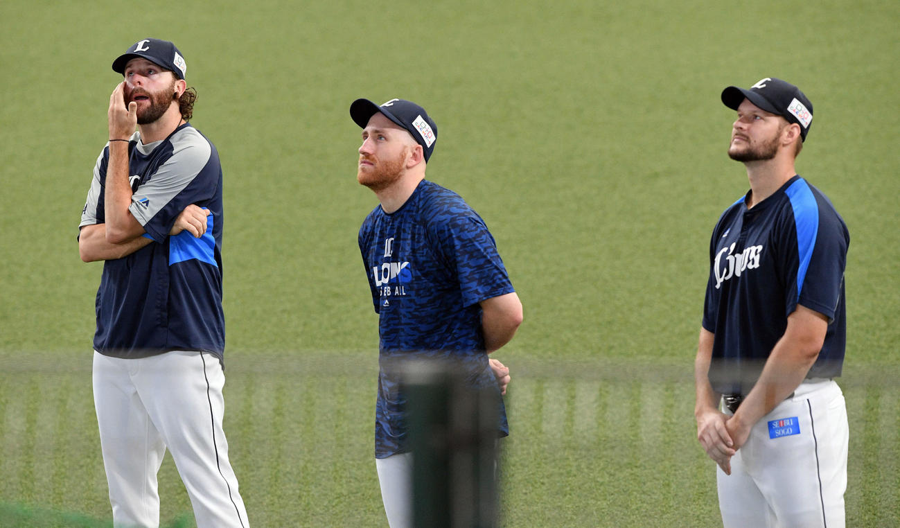 試合前練習中、サプライズで流された家族からのビデオメッセージを見つめる、左から西武ニール、ギャレット、ダーモディ（2021年6月20日撮影）