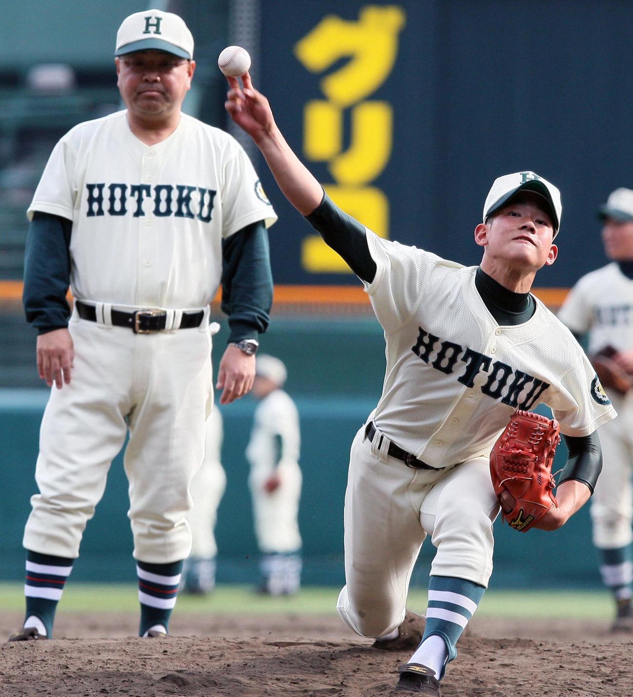 第83回選抜高校野球選手権大会・甲子園練習　永田裕治監督（左）が見守る前で投球する報徳学園・田村伊知郎（2011年3月19日）