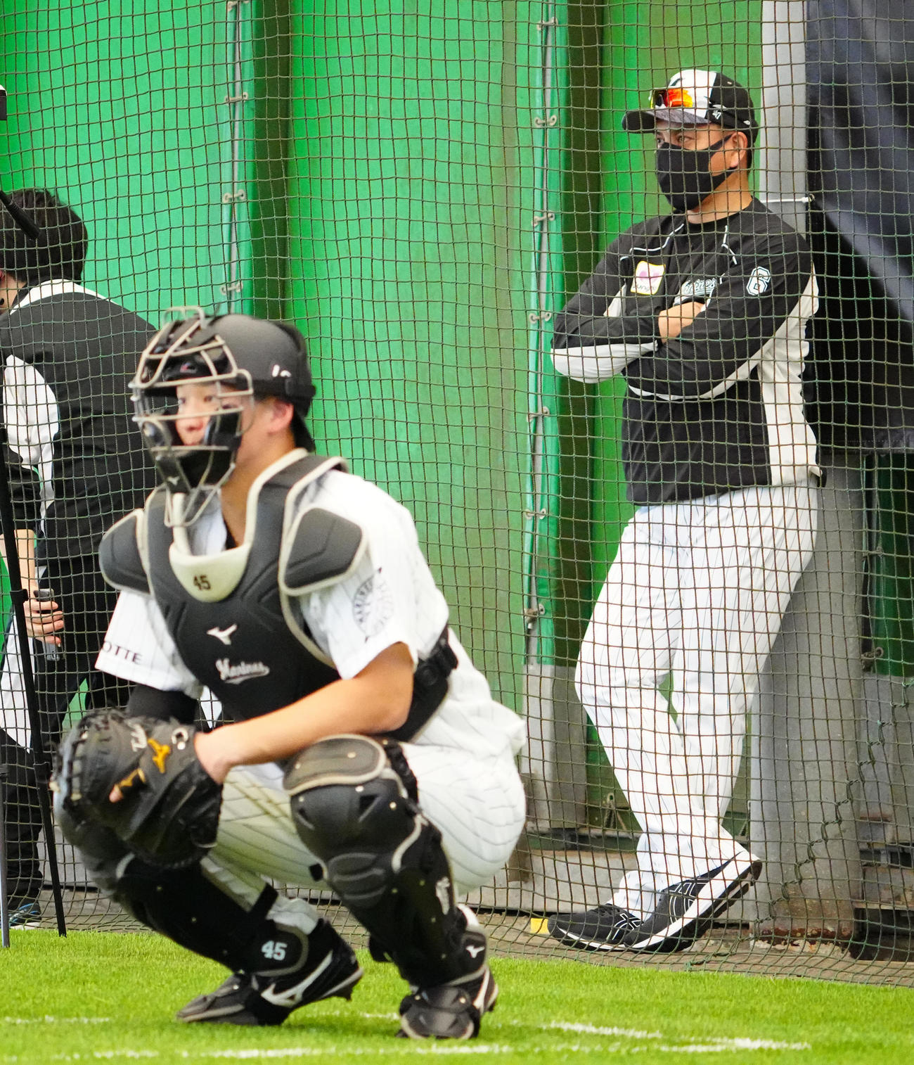 ロッテ石垣島キャンプ初日、ブルペン入りした佐々木朗の投球を見つめる井口監督（右）