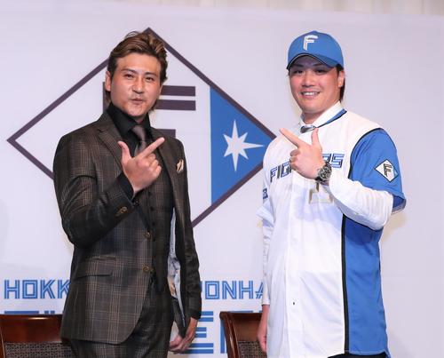 日本ハムのユニホームに袖を通し新庄剛志監督（左）とポーズをとる伏見（2022年11月24日撮影）