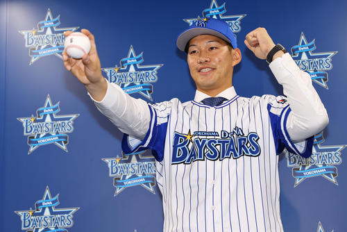 入団会見に臨んだDeNA京田はユニホームに袖を通し笑顔で写真に納まる＝2022年12月5日