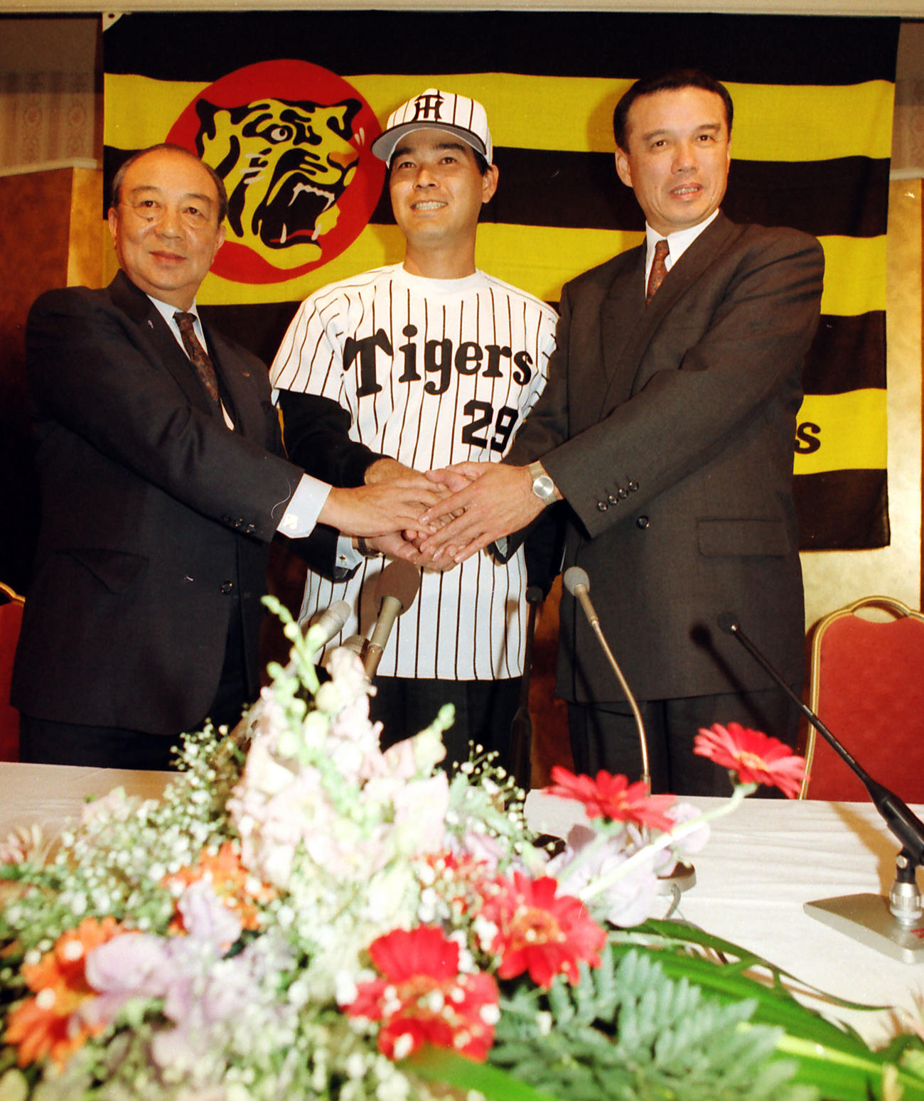 1993年12月8日、阪神FA入団会見で中村勝広監督（右）、三好一彦球団社長（左）と握手する石嶺和彦