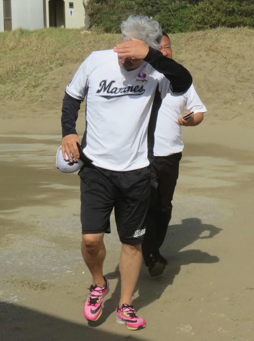 投手陣の砂浜ダッシュを視察に来るも、あまりの強風に顔を覆うロッテ吉井監督