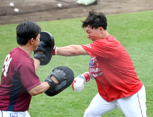 楽天雄平コーチ（左）が持つミットに強烈なパンチを打ち込む安田（撮影・山田愛斗）