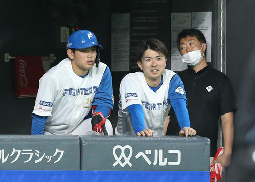ベンチから試合を見つめる日本ハム野村（左）と上沢（2022年6月撮影）