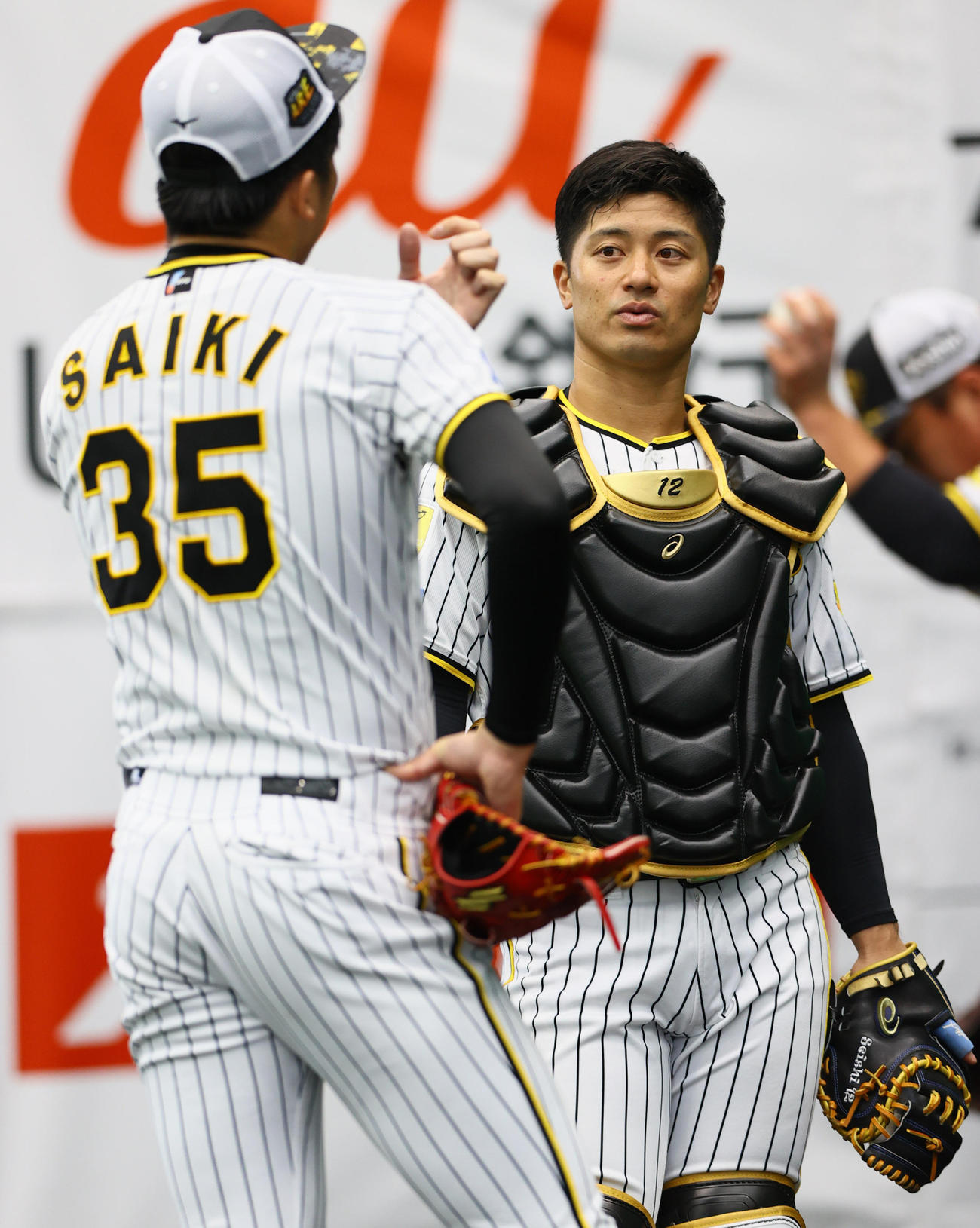 ブルペンで阪神才木浩人（手前）と話し込む坂本誠志郎（2024年2月10日撮影）