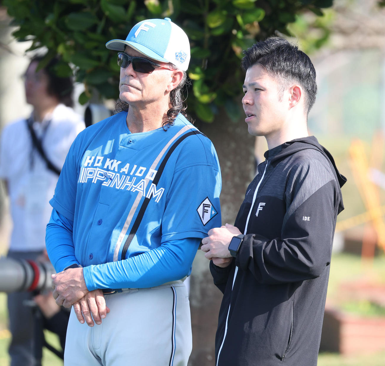 DeNA対日本ハム　試合前、日本ハムの練習を見つめる元監督のヒルマン氏（左）（2024年2月15日撮影）