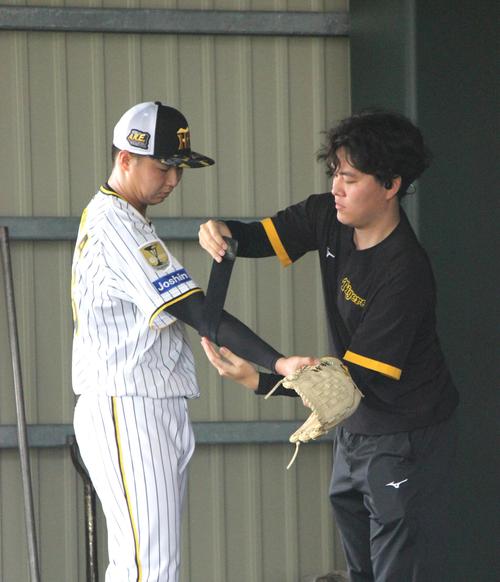 肘にパルススローと呼ばれる機器を装着する阪神津田淳哉（撮影・柏原誠）