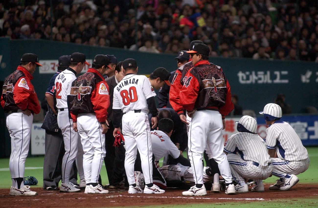 右足をいためた小久保裕紀は担架でベンチ裏に運ばれる。左は王貞治監督（2003年3月6日撮影）
