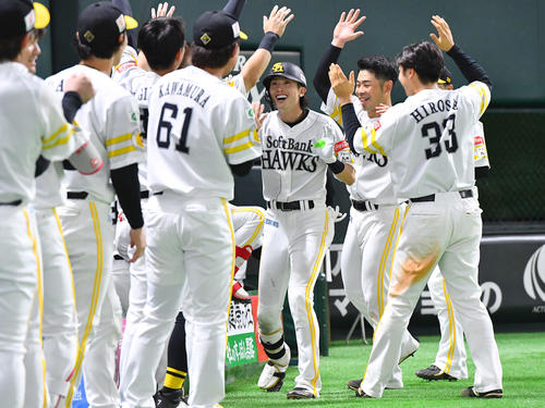 ソフトバンク対ロッテ　8回裏ソフトバンク2死、右中間へ勝ち越し本塁打を放った周東（中央）は、ナインからの祝福に笑顔を見せる（撮影・岩下翔太）