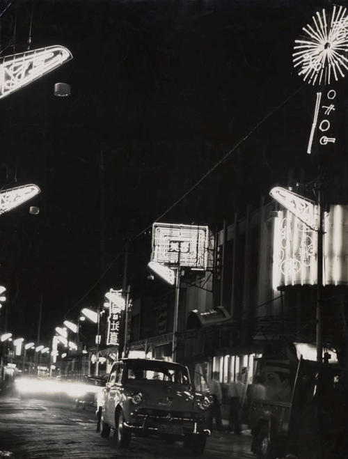 尼崎中央商店街の夜景。右上に丸い、中央に四角い「春美」のネオンが見える（55年撮影、兵庫県尼崎市立地域研究史料館所蔵）