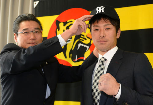 17年11月、阪神入団発表で、嶌村聡球団副本部長（左）から帽子をかぶせてもらう山崎憲晴