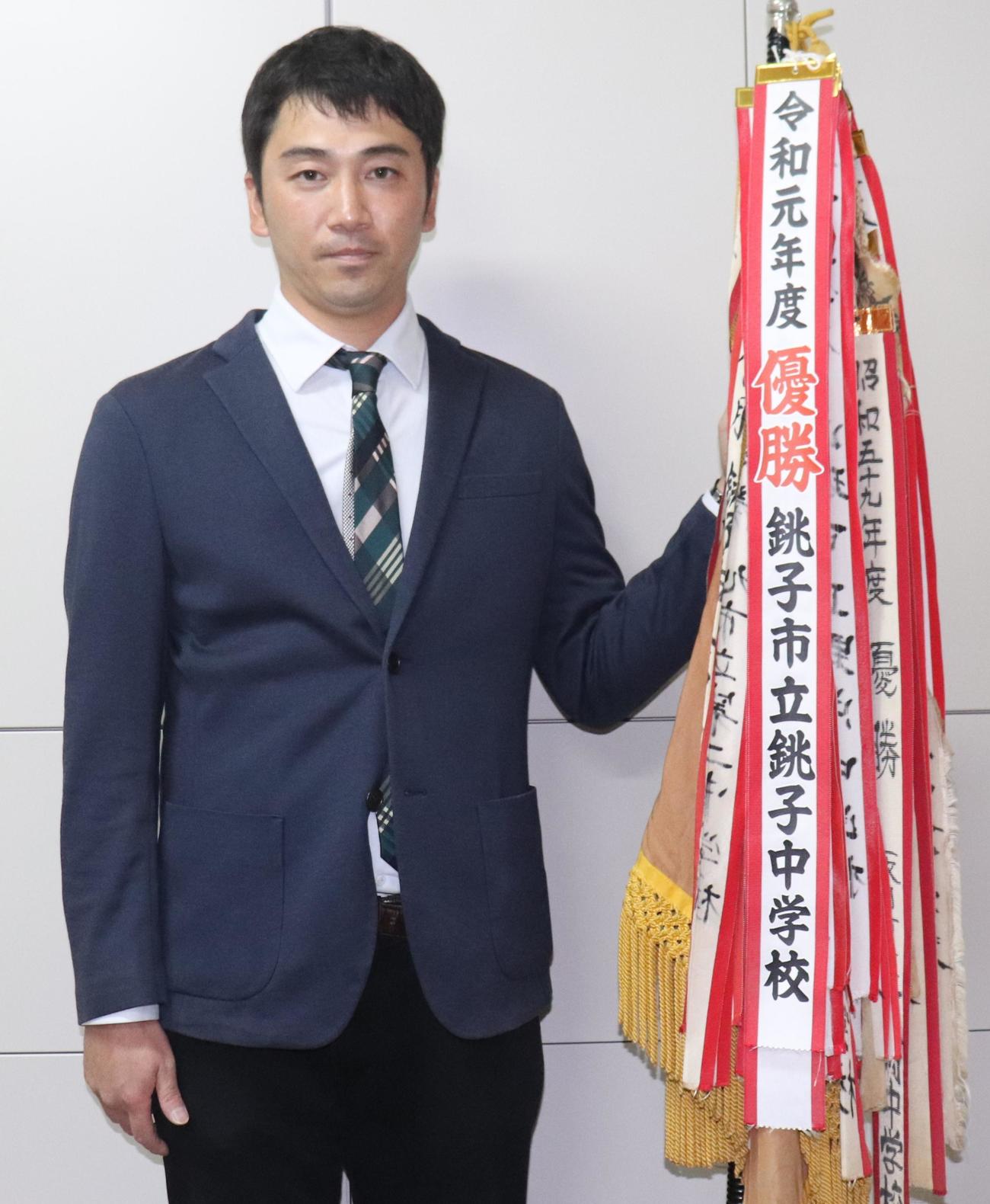 大会優勝旗を持つ千葉・銚子中野球部の斉藤之将監督
