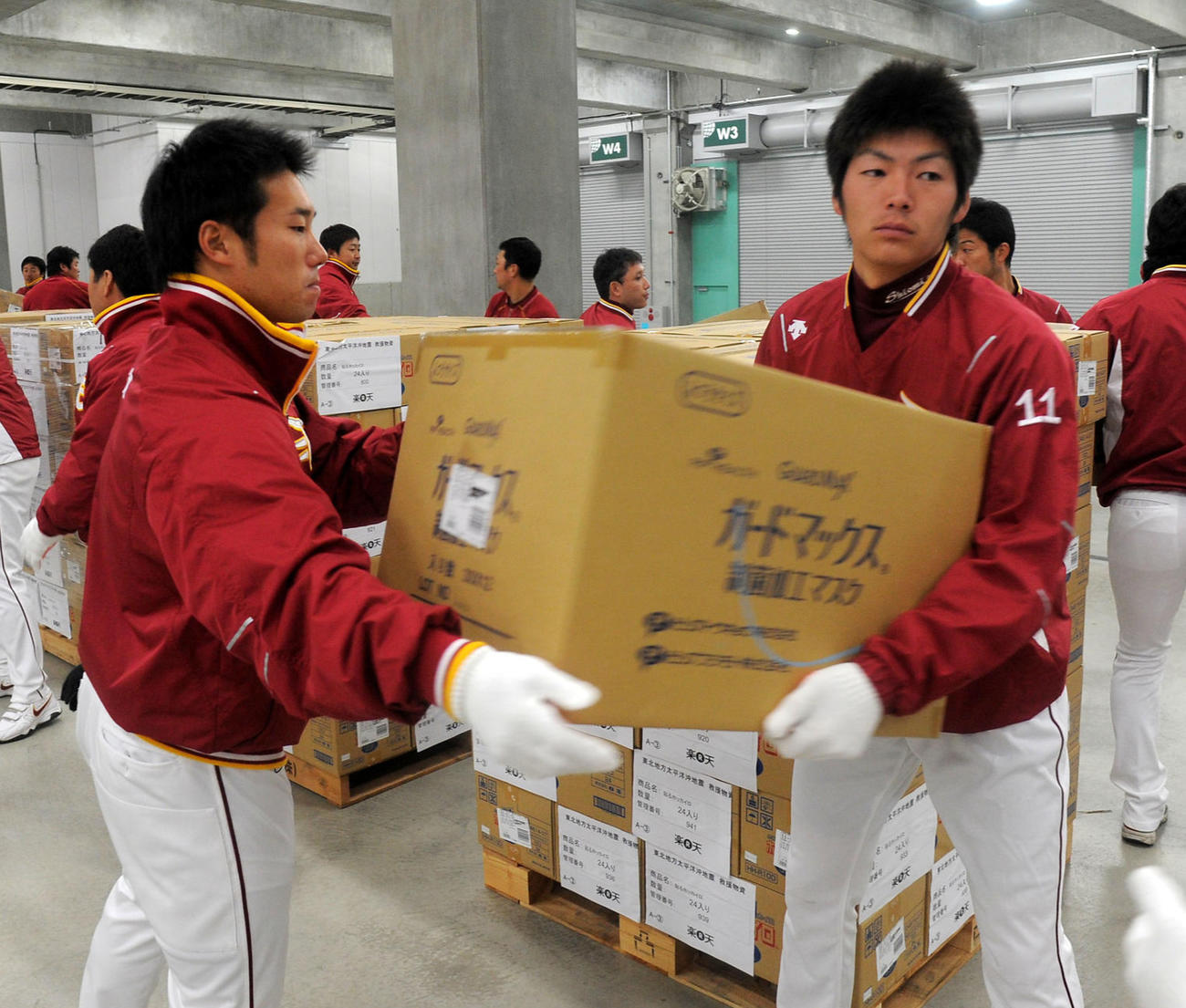 11年3月、救援物資をトラックへ積み込む塩見（右）