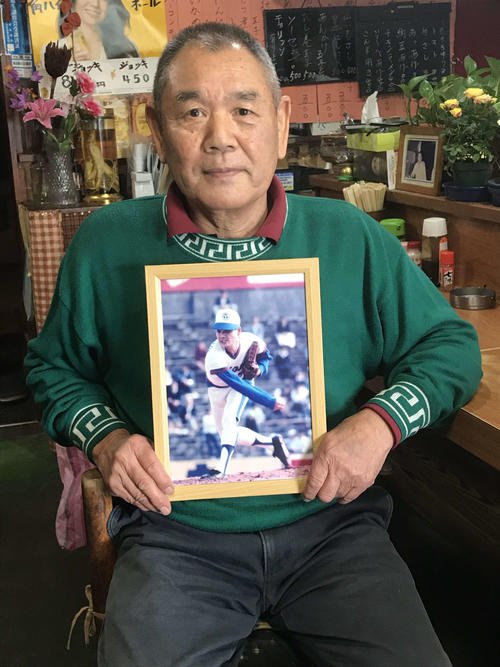 現役時代の写真を手にする田中氏