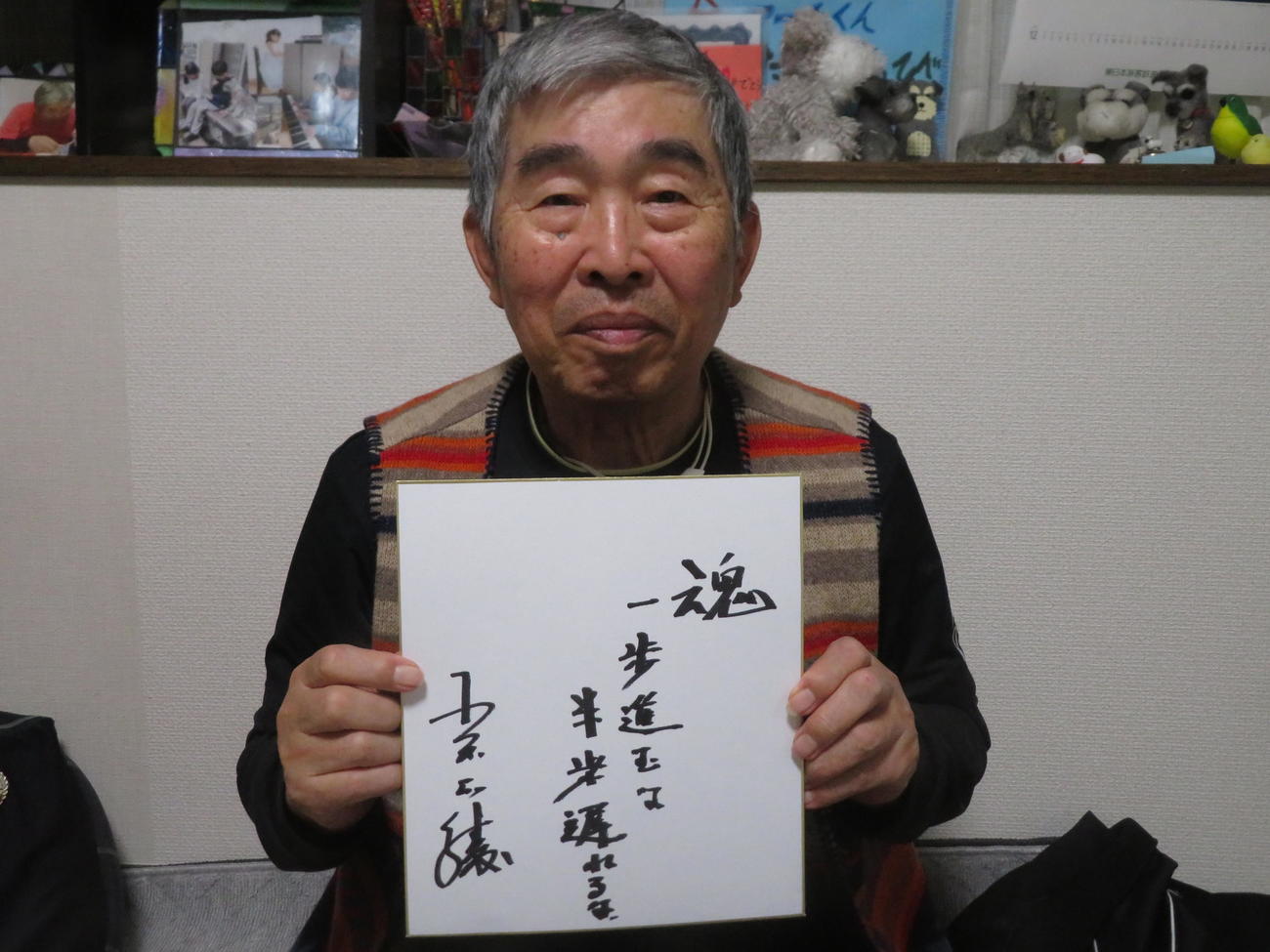 サインを書いた色紙を手に笑顔で写真に納まる小谷氏（撮影・久保賢吾）