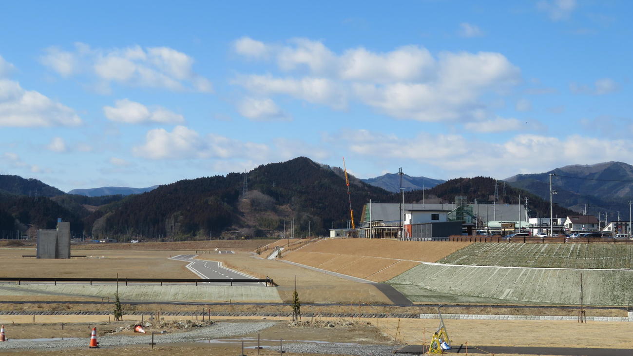 21年3月、写真左半分が震災遺構のビルも残る岩手・陸前高田の旧市街地。右半分が約10メートルかさ上げされた新市街地