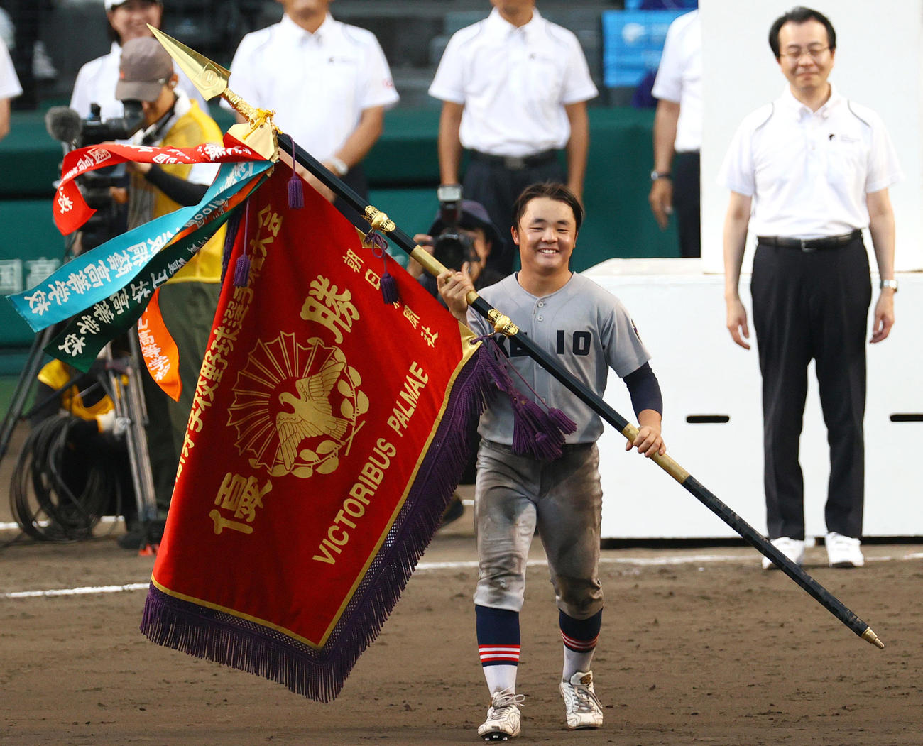 深紅の優勝旗を手に、笑顔をみせる慶応・大村主将