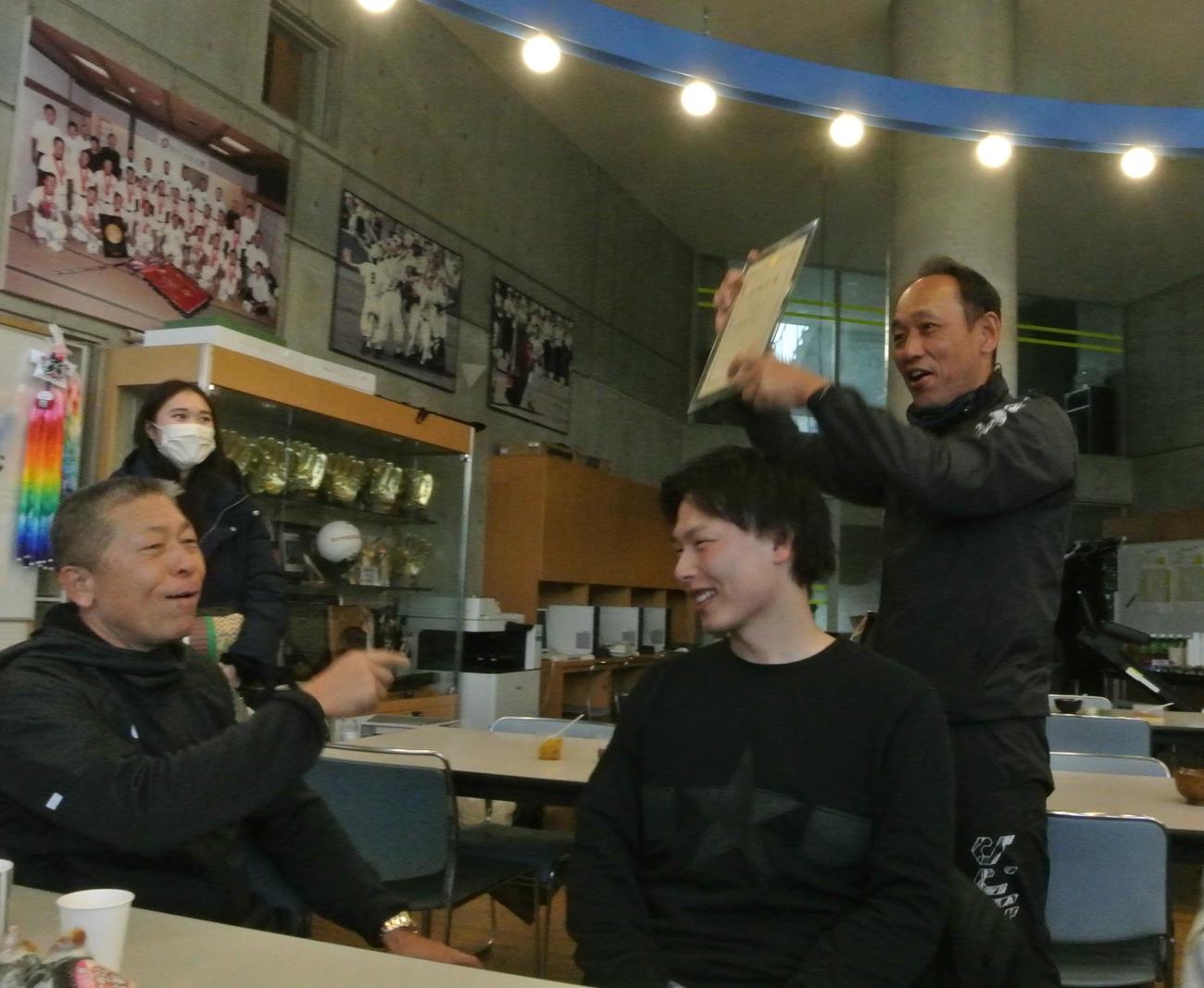 23年12月、岩切さん（右から2人目）の合格証書を掲げてOBたちに披露する日大三・三木監督（右）と感心する小倉前監督