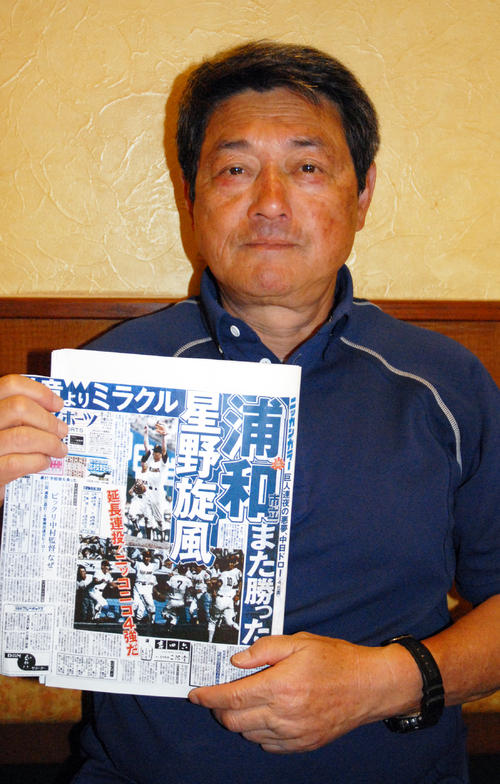 当時の日刊スポーツの一面記事を手にする中村三四監督