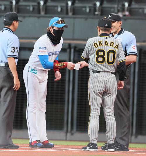 日本ハム対阪神　試合前のメンバー表最終確認で会話する岡田監督（右）と新庄監督（撮影・加藤哉）