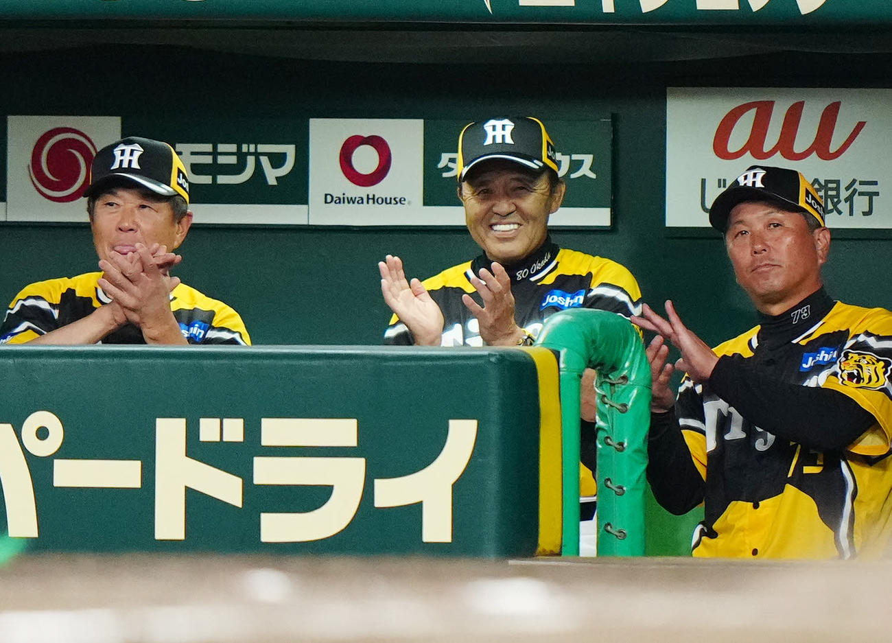 阪神対巨人　7回裏、ベンチで笑顔を見せる阪神岡田監督（中央）（2023年7月26日撮影）