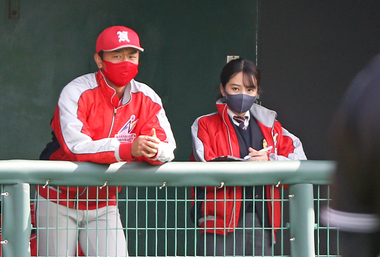 11月6日、スコアブックをつけながら戦況を見守る奈良学園大・上原美穂主務（右）
