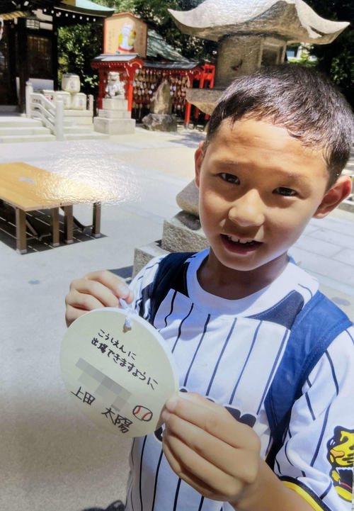 甲子園素盞嗚神社にて、「こうしえんに出場できますように」と書いた絵馬を手に写真におさまる、小学生時代の国学院久我山・上田太陽主将（両親提供、画像は一部加工）