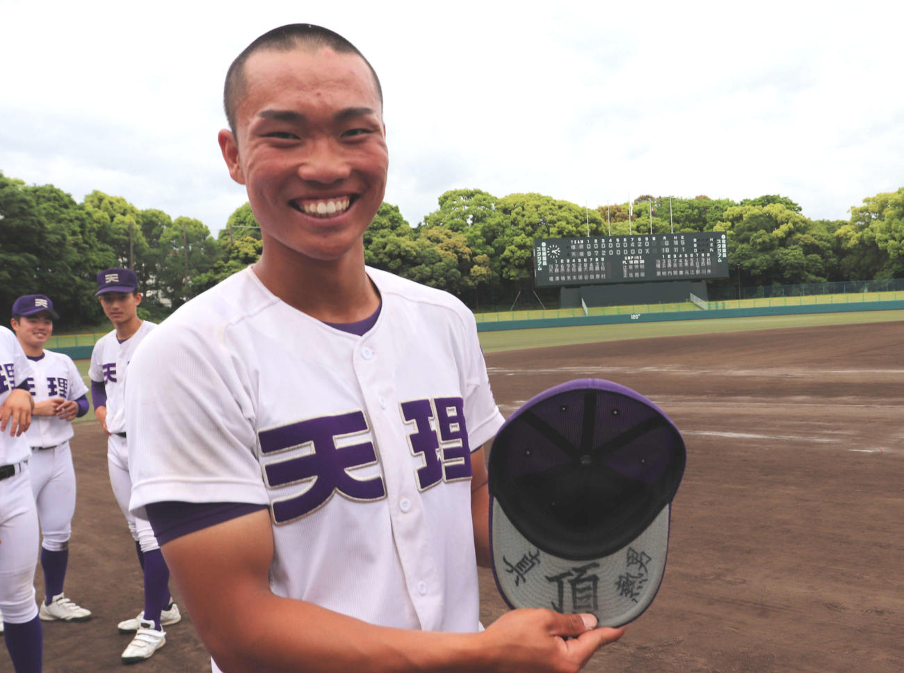帽子のつばを見せる天理の背番号12永野