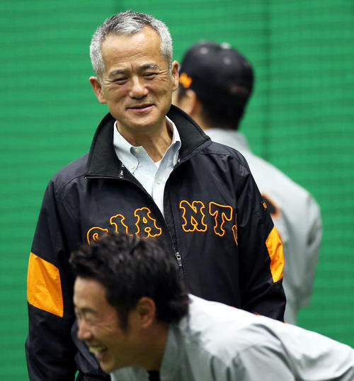 室内練習場で巨人亀井（手前）と談笑する春川編成本部次長兼国際部長（撮影・狩俣裕三）