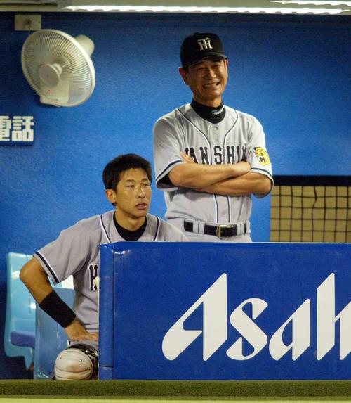 03年9月10日、ベンチで腕組みをしながら笑顔を見せる阪神星野監督。手前は矢野