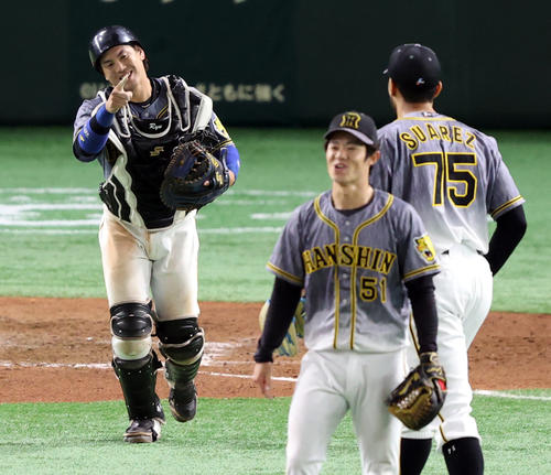 巨人対阪神　試合後、スアレス（右）と喜びを分かち合う梅野。手前は中野（撮影・狩俣裕三）