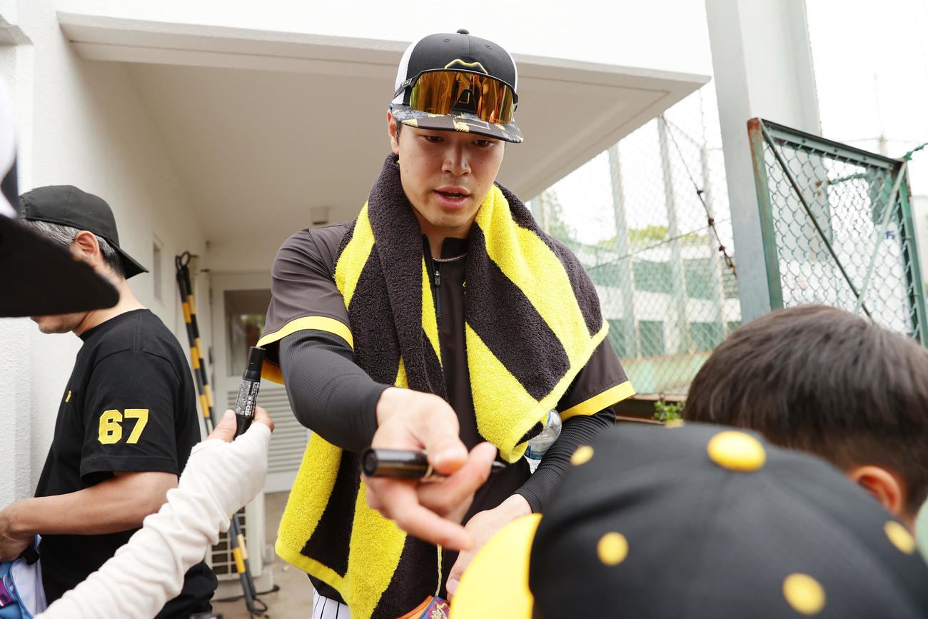 2軍に降格した阪神佐藤輝はノックを終え子どもたちにサインする（撮影・前田充）