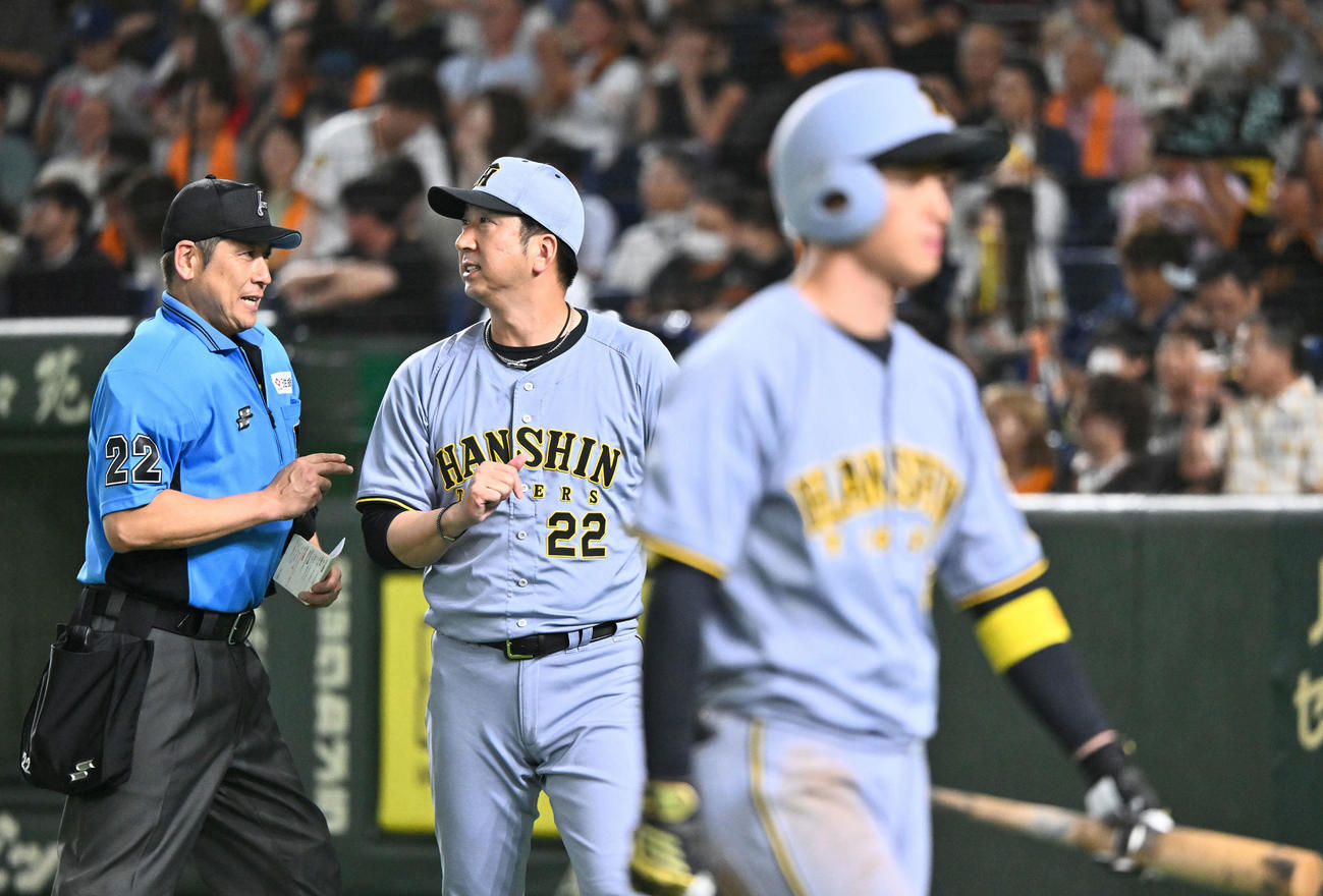 巨人対阪神　8回裏、交代を伝える阪神藤川監督。手前は空振り三振に倒れた近本（撮影・滝沢徹郎）