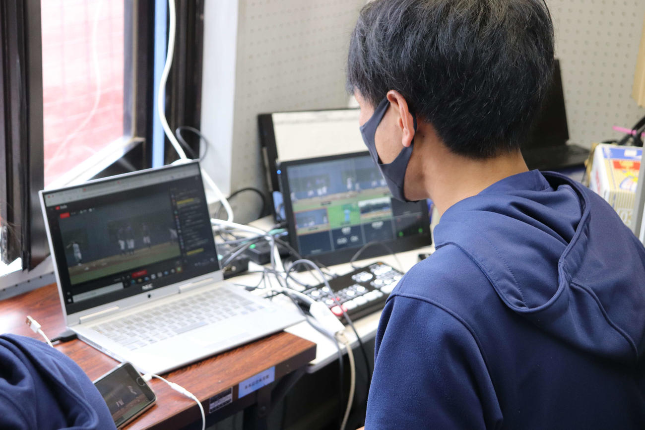 日体大対亜大　グラウンドの本部席からオープン戦の動画画面の切り換え操作をする日体大・大塚（撮影・保坂淑子）