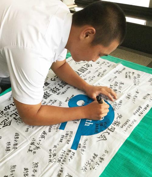 被災地熊本の球児に向け、「記念旗」にメッセージを書き入れる小倉の徳永直樹主将