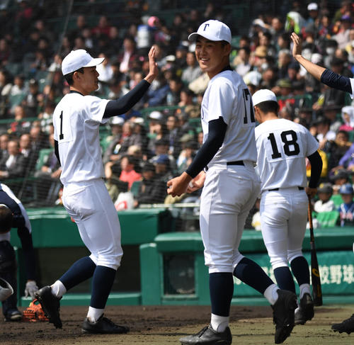習志野対東邦　2回無失点に抑えた石川（左）はナインとタッチを交わす（撮影・奥田泰也）