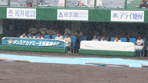 試合予定時間になっても開始されず、一塁側ベンチでグラウンドを見つめる旭川大高ナイン（撮影・浅水友輝）