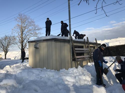 グランドに隣接した施設屋根の雪下ろしをする飯山ナイン（飯山高校野球部提供）