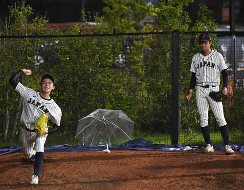 日本対パナマ　試合中、ブルペンで投球練習する佐々木（左）と奥川（撮影・横山健太）