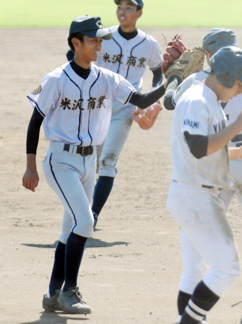米沢商エース遠藤（左）は開幕試合を完投勝利で飾り、仲間とタッチをかわす
