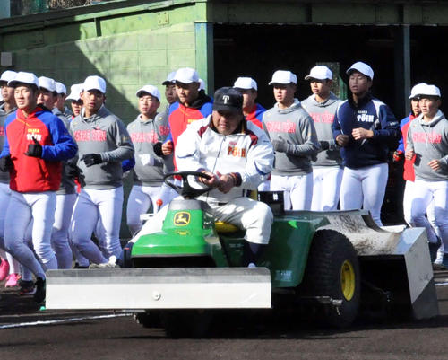 ランニングする大阪桐蔭ナインの横で整備車に乗ってグラウンドをならす西谷浩一監督（撮影・石橋隆雄）