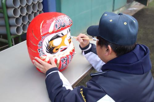 山梨学院　今年の必勝を祈願し、だるまの目に「叶」の文字を書く吉田洸二監督（撮影・保坂淑子）
