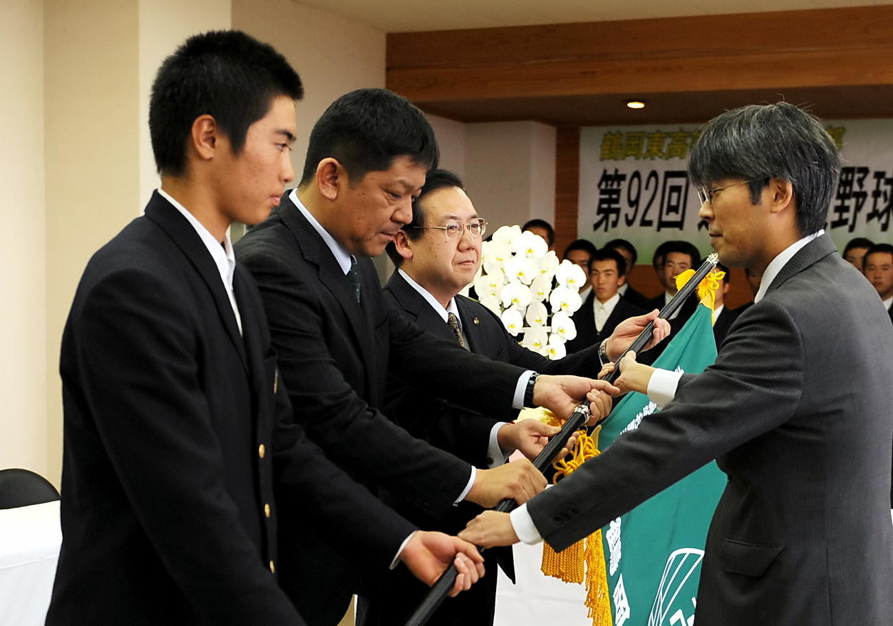 選抜旗を受け取る鶴岡東の、左から鈴木主将、佐藤監督、斎藤校長