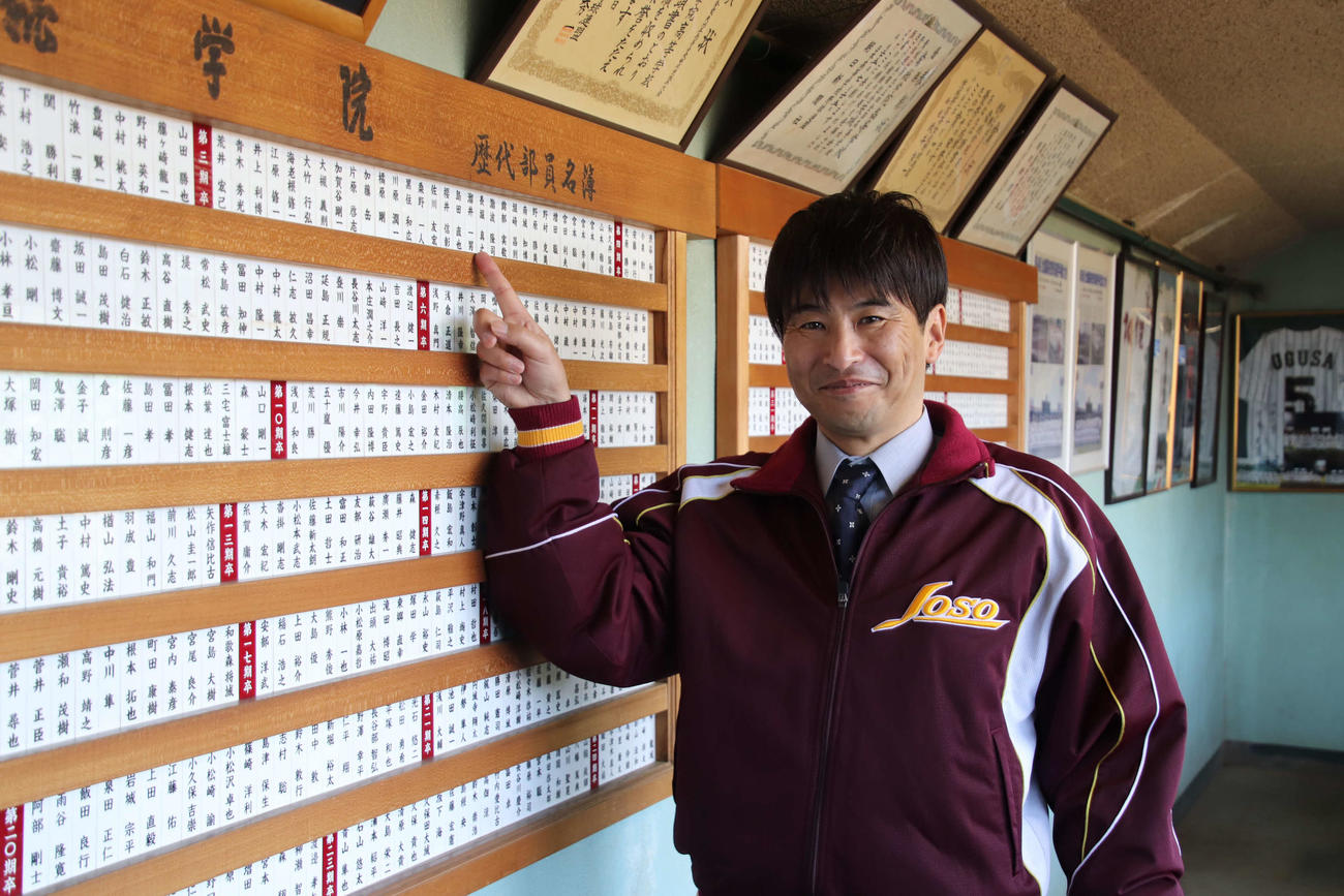 常総学院の投手コーチに就任した島田氏は、歴代部員名簿から第3期生の自分の名前を指さす（撮影・保坂淑子）