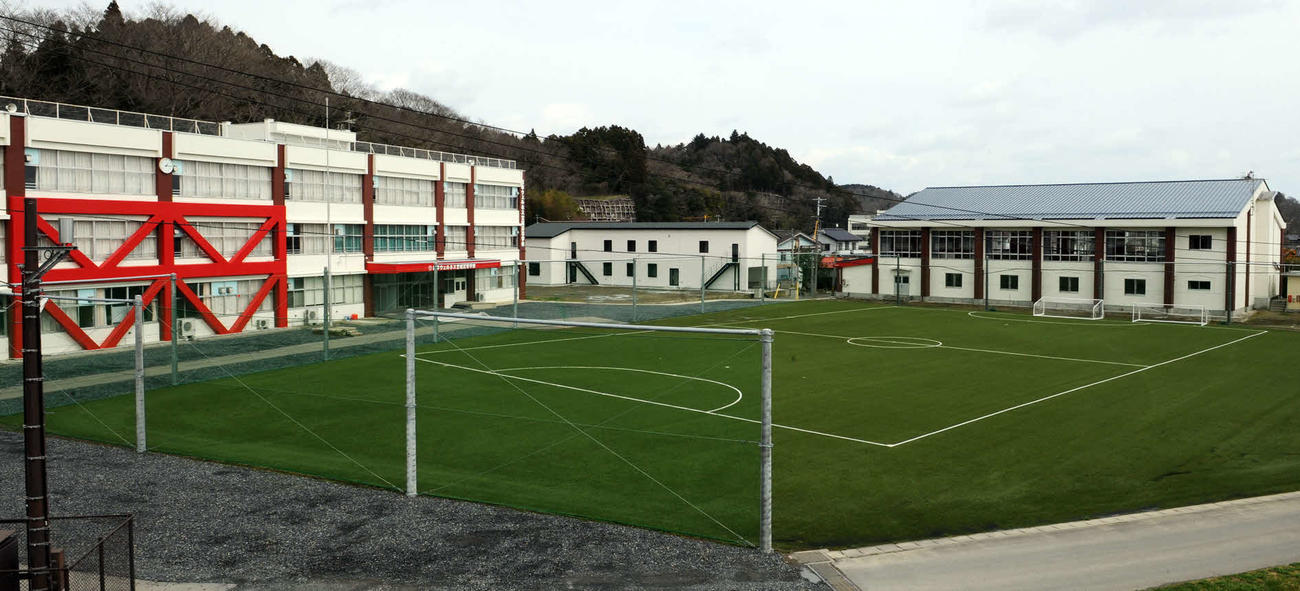 日本ウェルネス宮城高は天然芝のグラウンドを囲むように、左から3階建て校舎，学生寮、体育館を併設