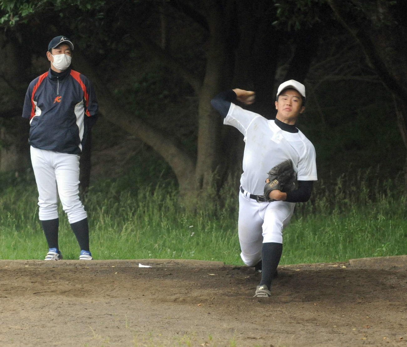 米山監督（左）が見守る中、投球練習をする肥沼