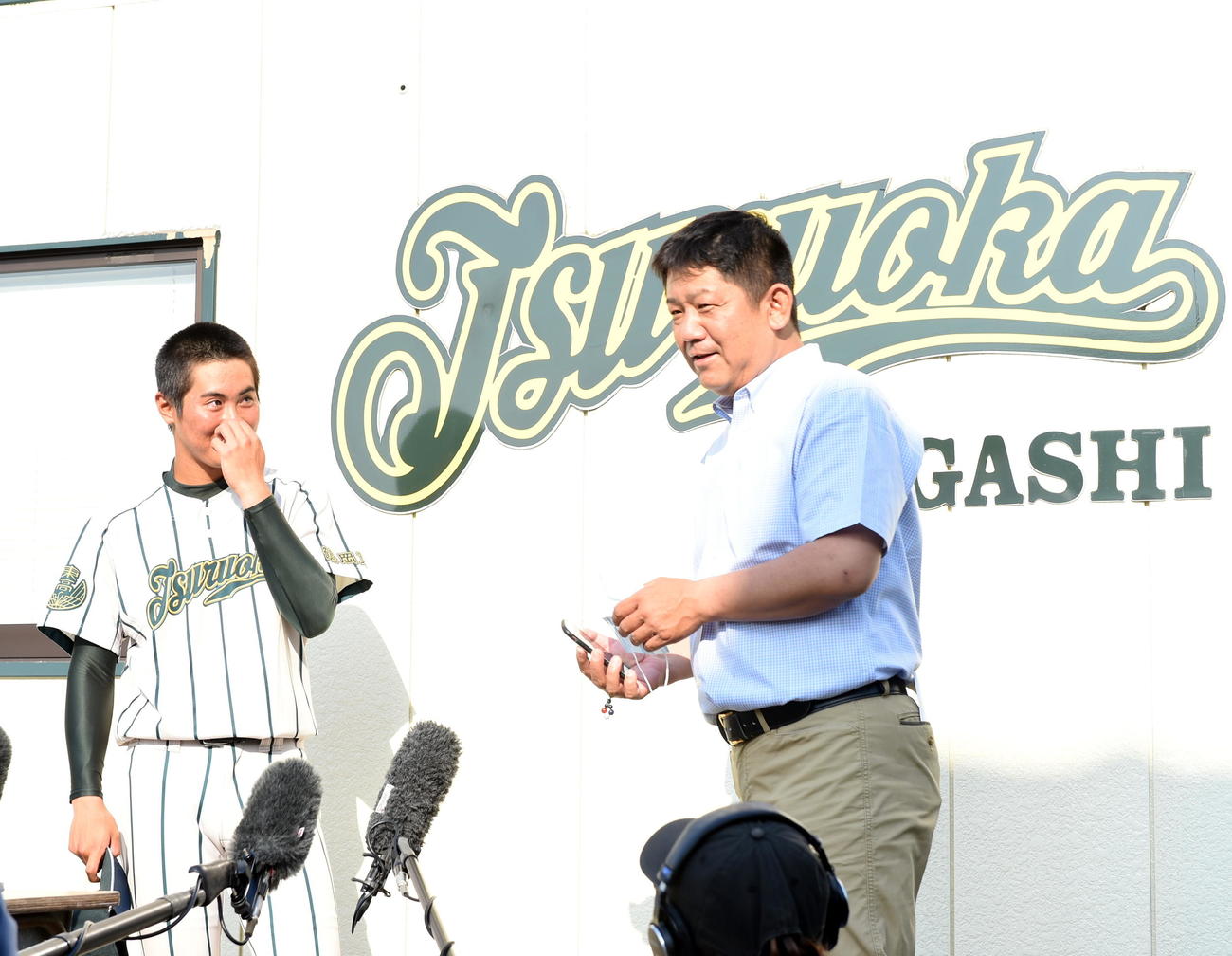 鶴岡東・佐藤監督（右）からネットニュースを見せられ、甲子園交流試合開催を伝えられた鈴木主将（撮影・山田愛斗）